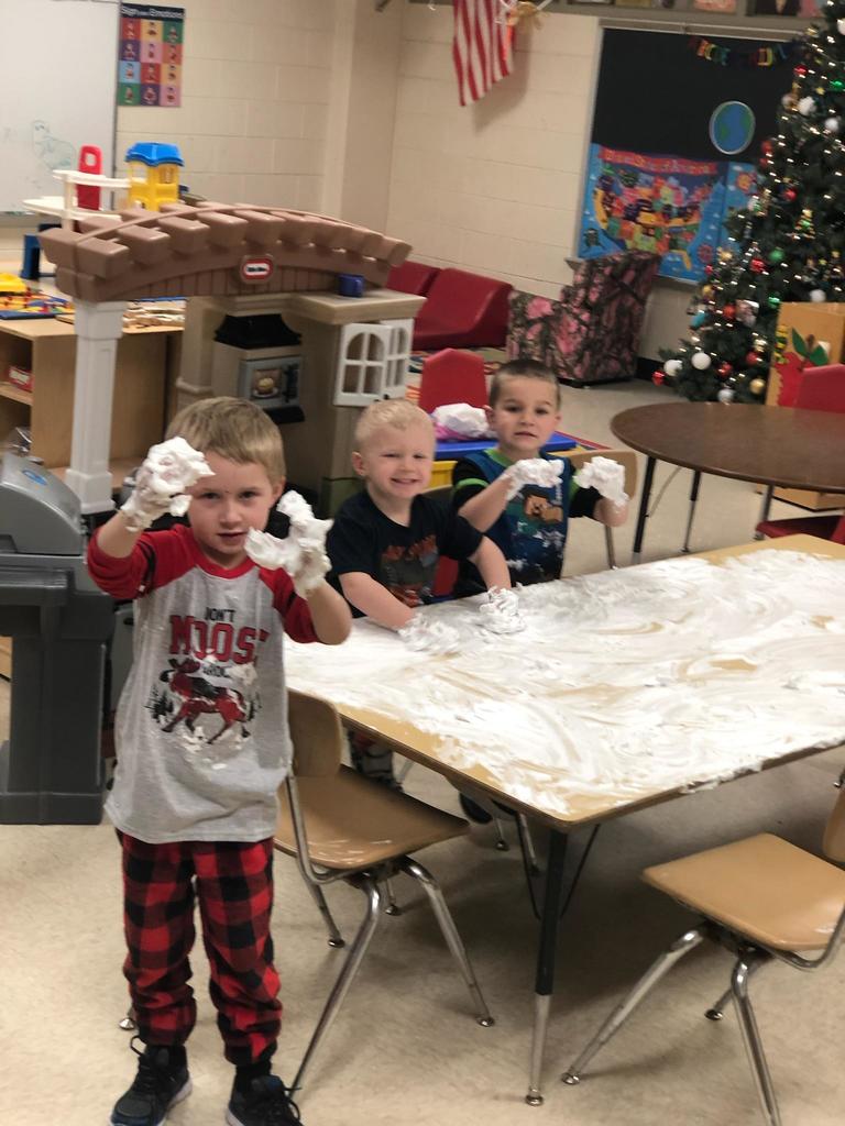 Kids playing with shaving cream on a table.